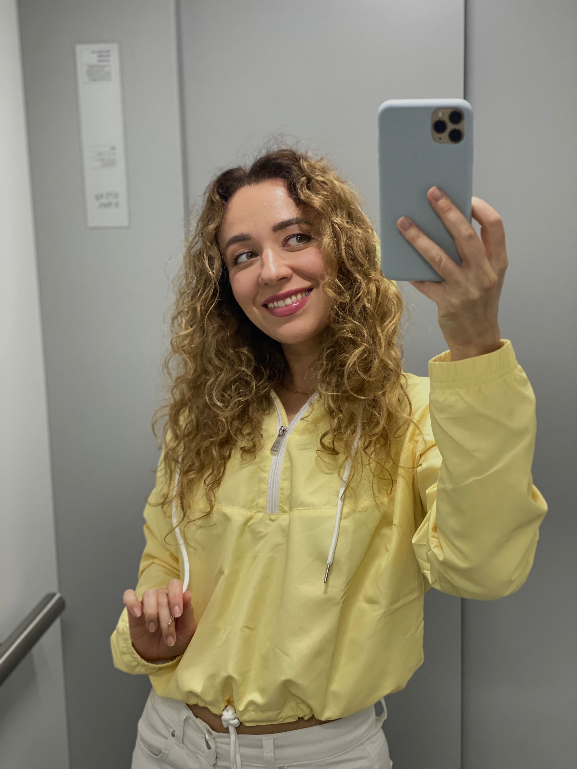 Female model in lightweight yellow windbreaker with elastic cuffs and side pockets, styled effortlessly for everyday chic