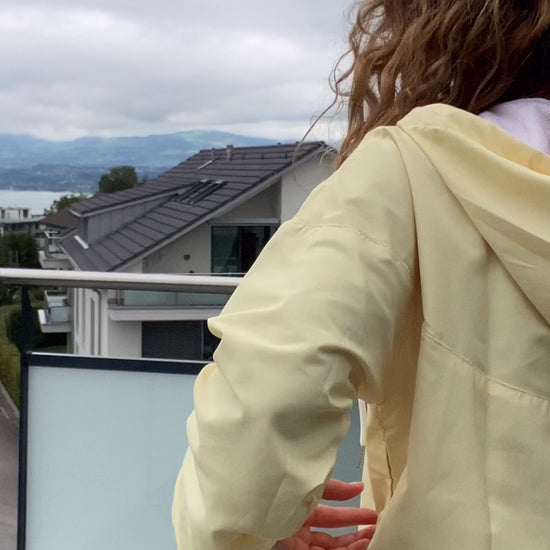 Video of a female model in trendy soft washed yellow windbreaker, styling it effortlessly for everyday autumn fashion.