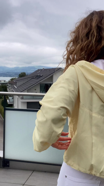 Video of a female model in trendy soft washed yellow windbreaker, styling it effortlessly for everyday autumn fashion.