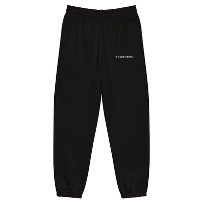 Heavyweight sweatpants in Black with soft brushed fleece, white “coziness” embroidery, deep side pockets, elastic cuffs, and relaxed street-style fit.