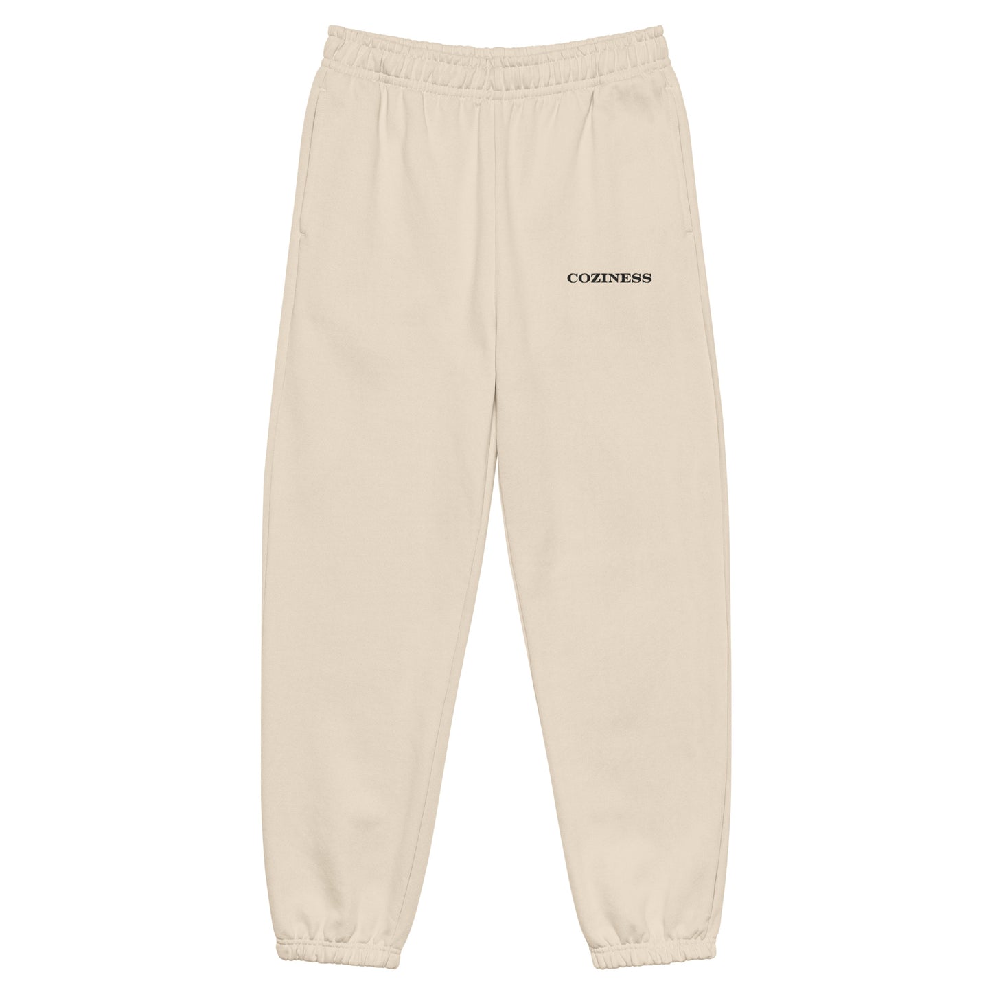 Heavyweight sweatpants in Dust with soft brushed fleece, black “coziness” embroidery, deep side pockets, elastic cuffs, and relaxed street-style fit.