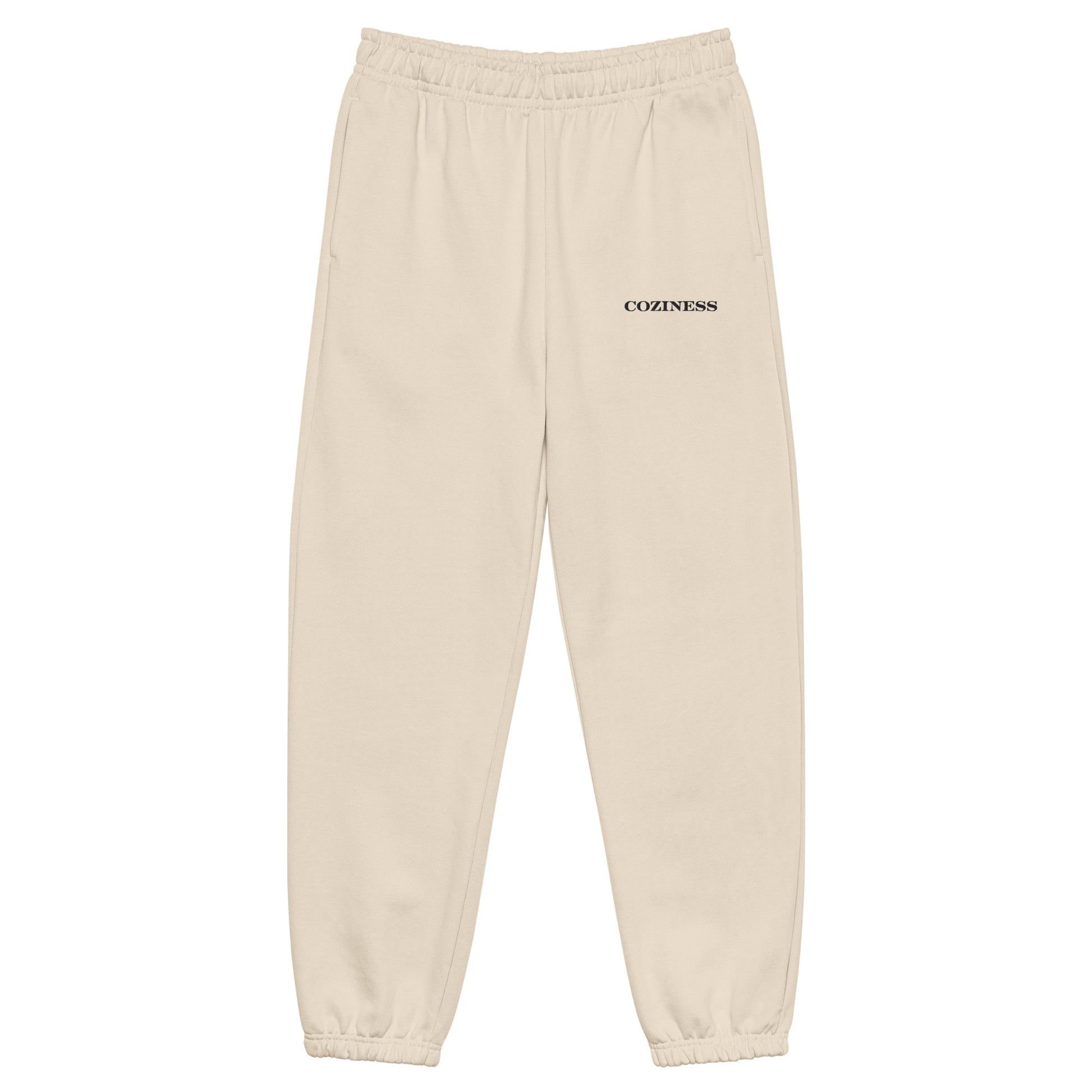 Heavyweight sweatpants in Dust with soft brushed fleece, black “coziness” embroidery, deep side pockets, elastic cuffs, and relaxed street-style fit.