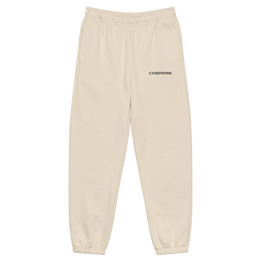 Heavyweight sweatpants in Dust with soft brushed fleece, black “coziness” embroidery, deep side pockets, elastic cuffs, and relaxed street-style fit.